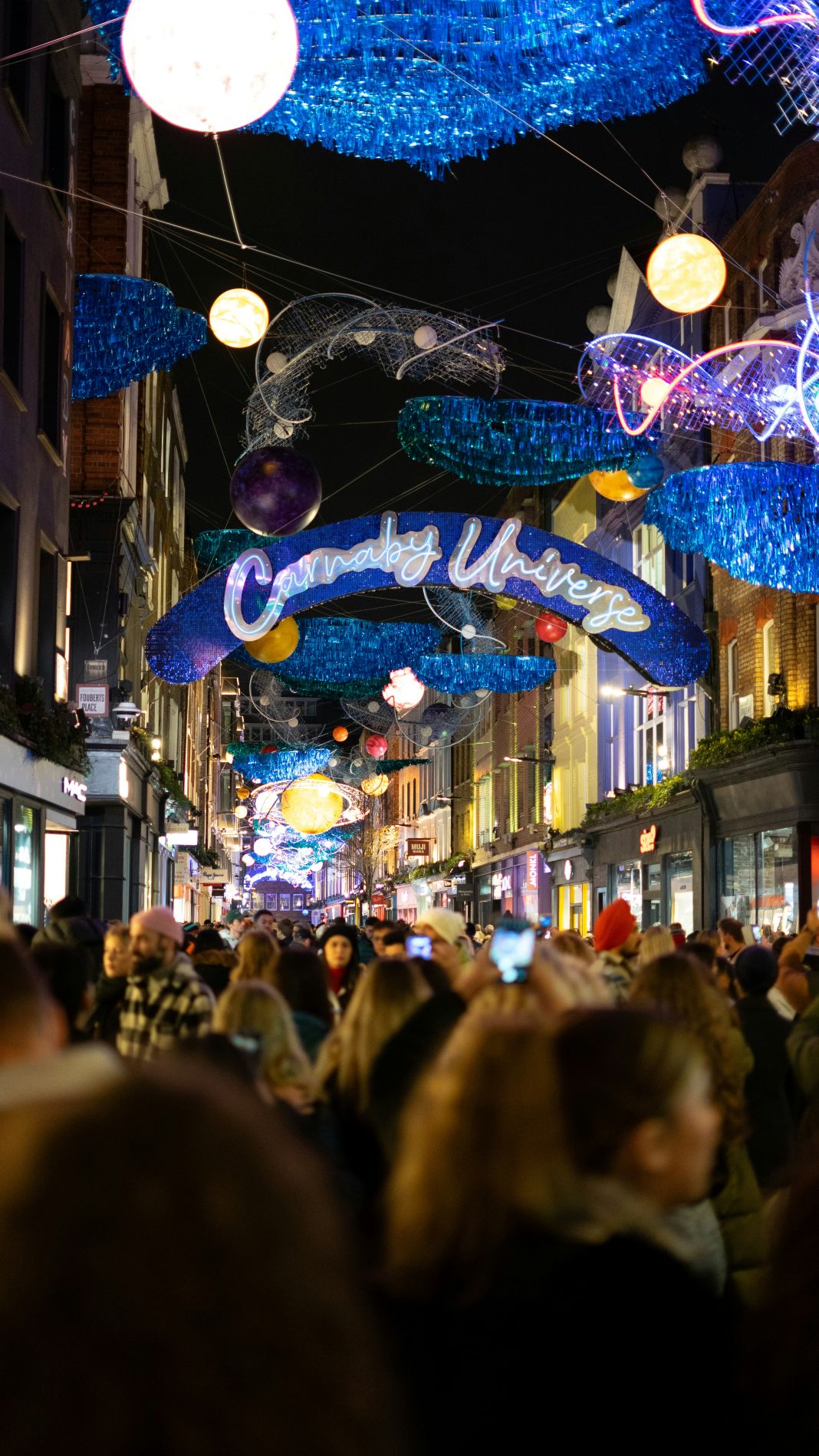 a photo of carnaby street shopping in central london at night which looks very busy
