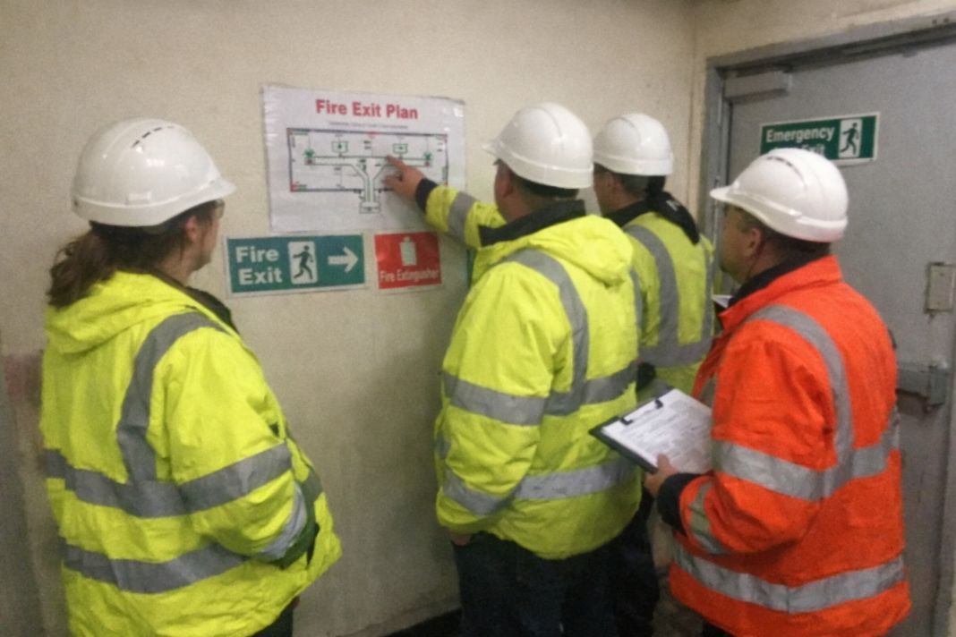 A representative image of a team in high-vis jackets conducting a site tour and reviewing fire exit routes