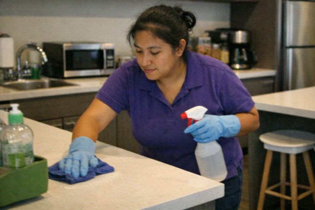A representative image of an office cleaner cleaning a modern shared office kitchen