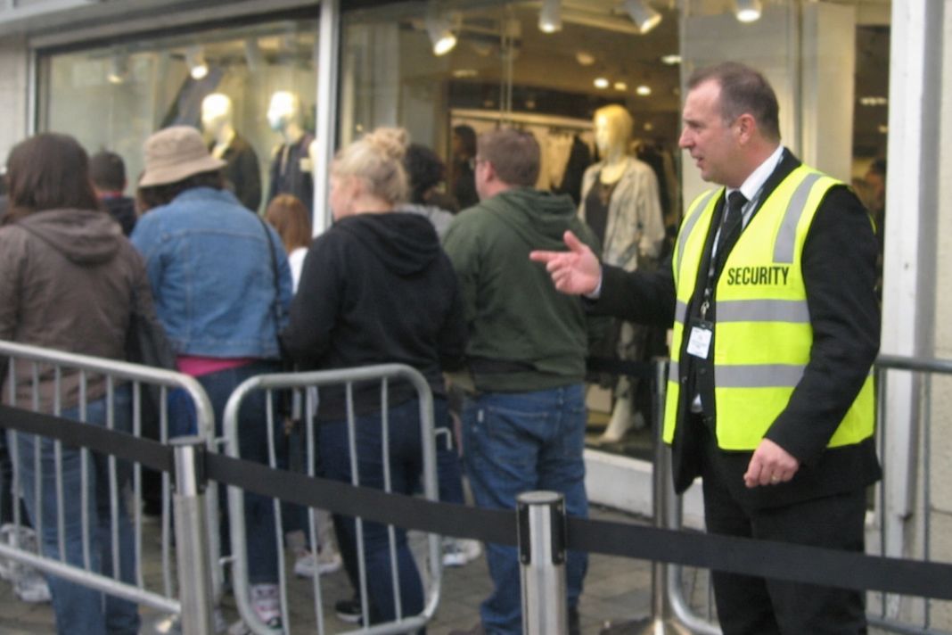 A representative image of an outdoor queue outside a clothing store with barriers and a visible staff member