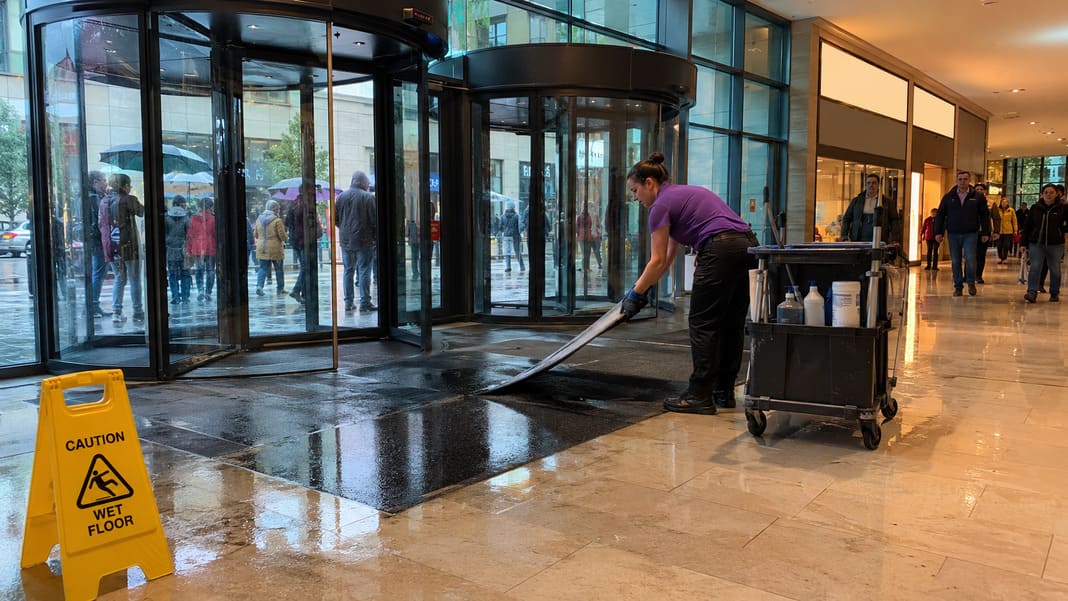 A photo of a cleaner cleaning up after flooding in a shopping centre entrance