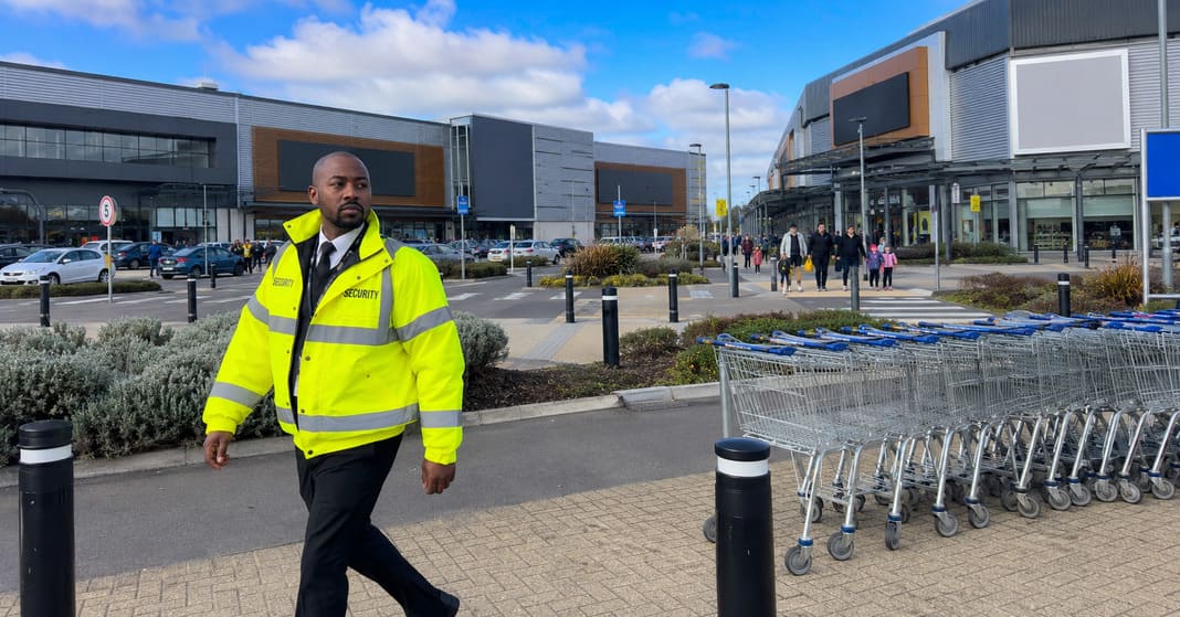 A photo of a security guard patrolling outside of retail stores in the UK