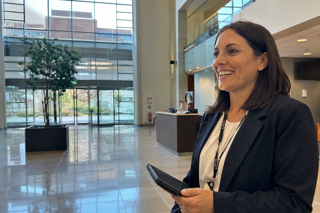 Facilities manager holding a tablet and smiling in a corporate building lobby