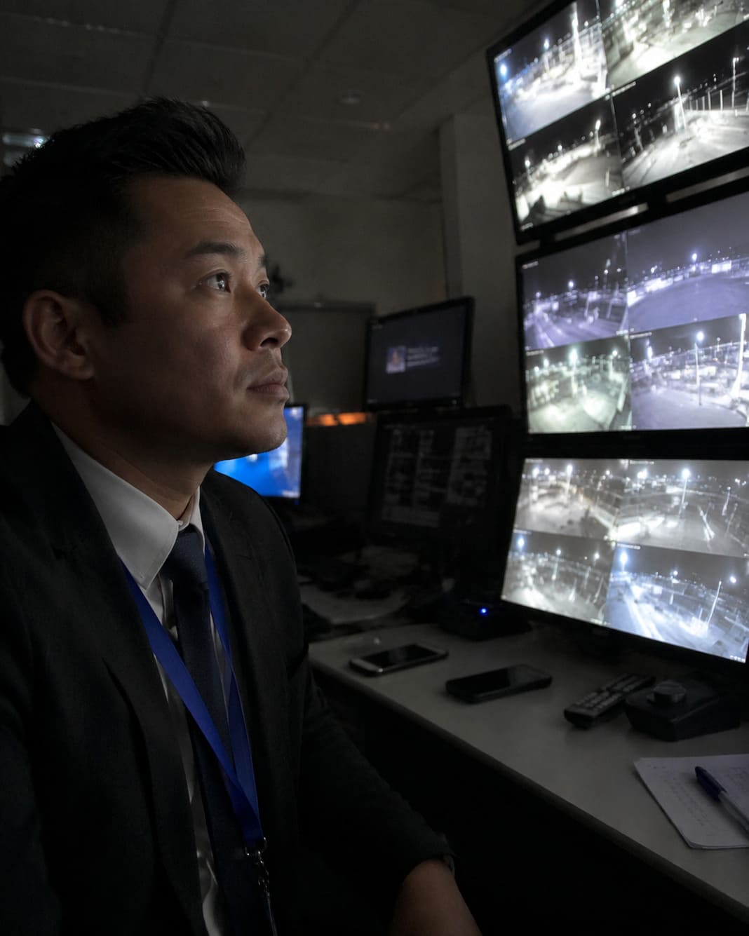 Night CCTV operator verifies suspicious activity across remote commercial surveillance camera feeds.