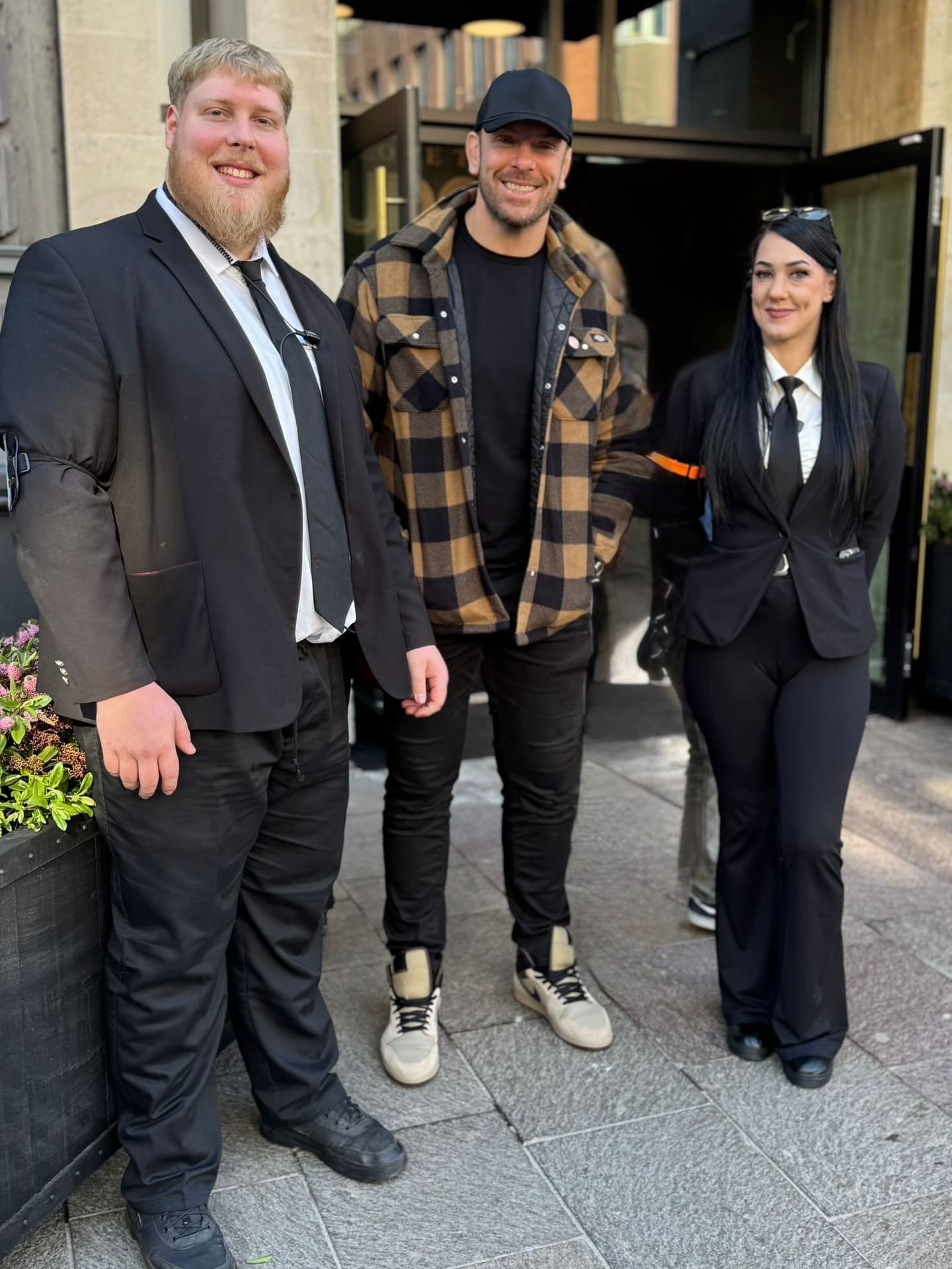 SIA licensed door supervisors posing with a client outside a secure hospitality venue entrance