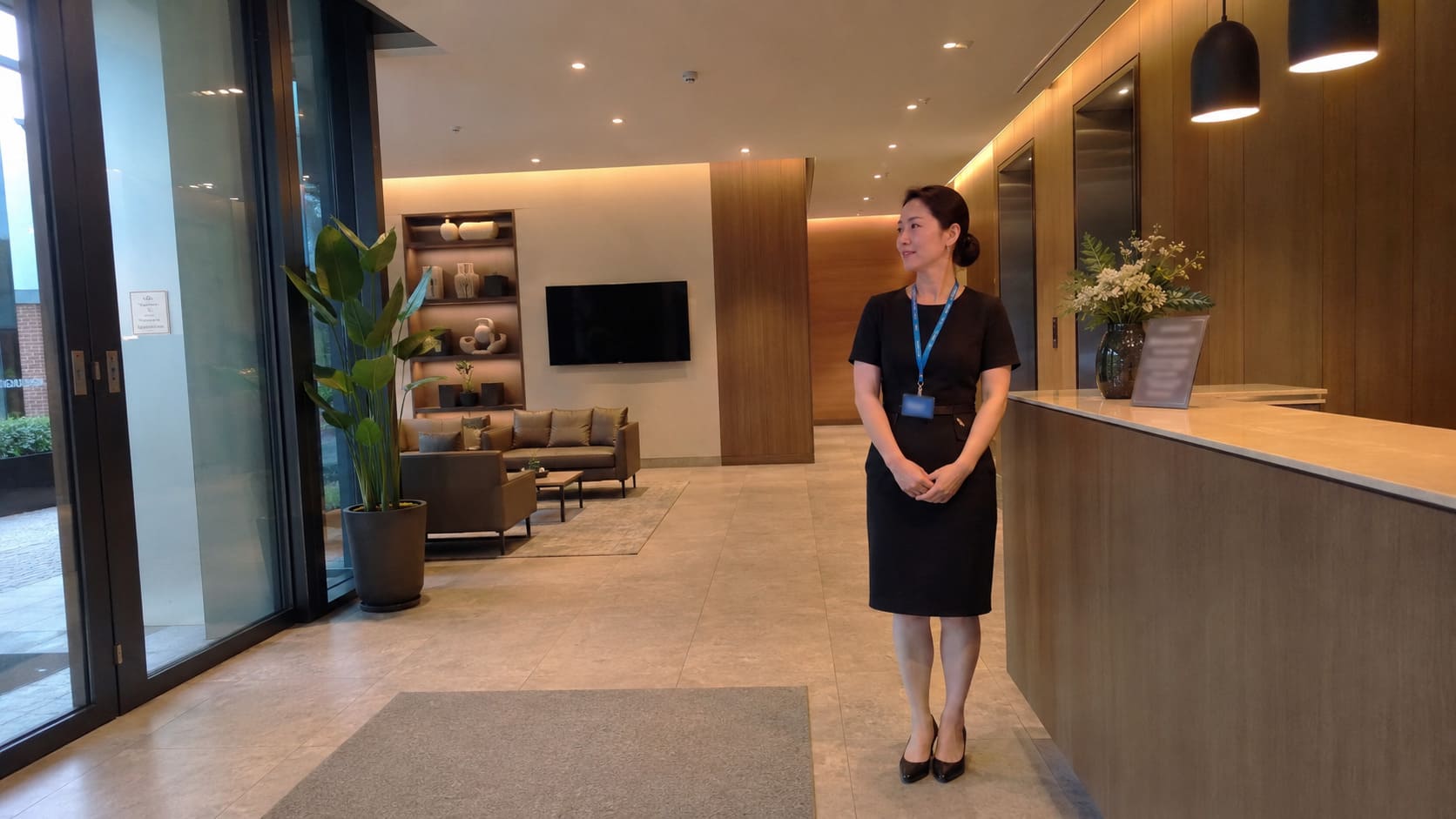 Receptionist standing beside an illuminated hotel front desk - Illustrative Image