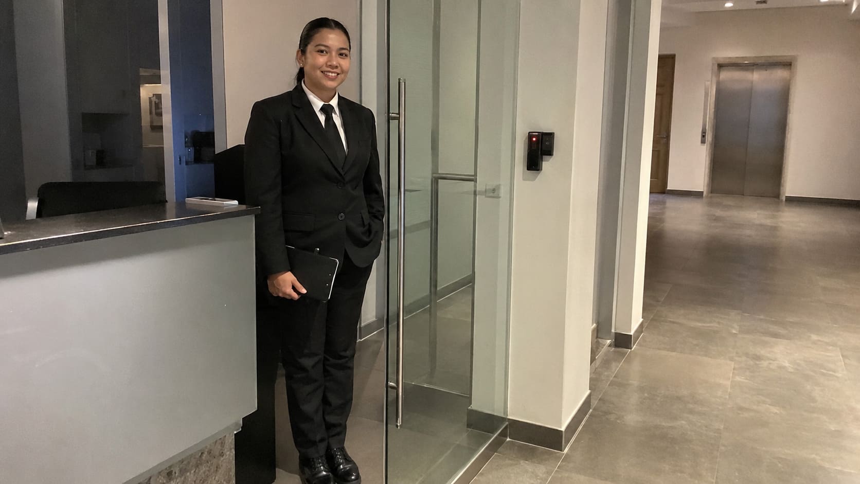Suited security officer standing beside a corporate reception desk - Illustrative Image Suited security officer standing beside a corporate reception desk - Illustrative Image