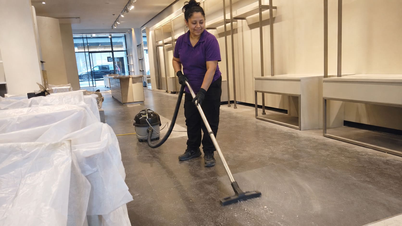 After builders cleaner vacuuming construction dust inside refurbished retail store After builders cleaner vacuuming construction dust inside refurbished retail store
