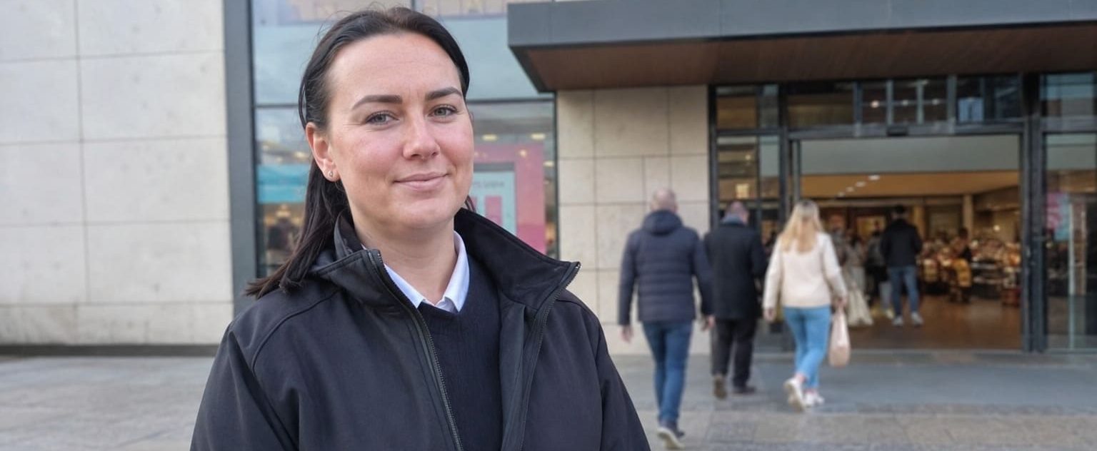 Female security officer guarding busy retail building entrance