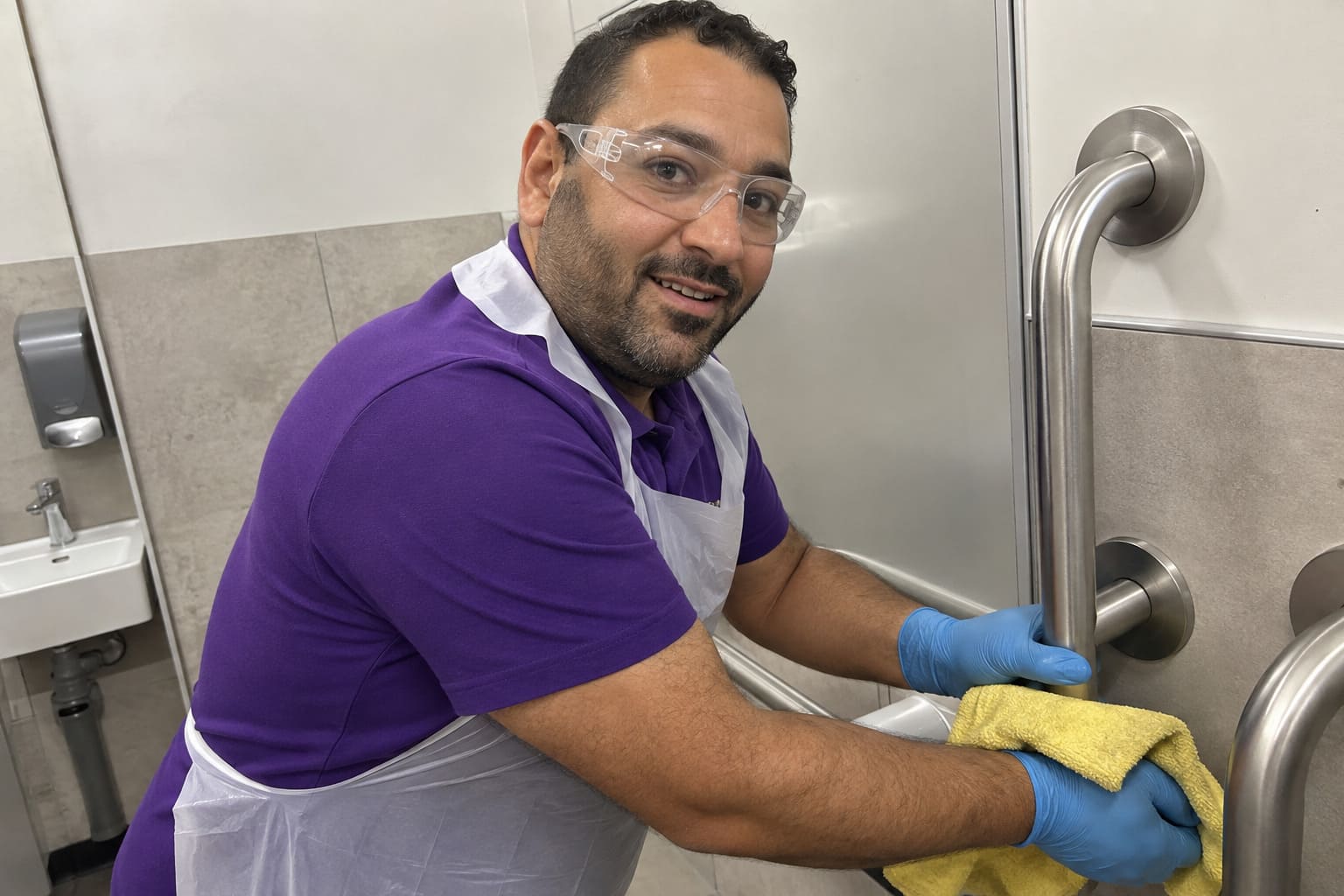 Hospital cleaner sanitising washroom fixtures during specialist healthcare cleaning