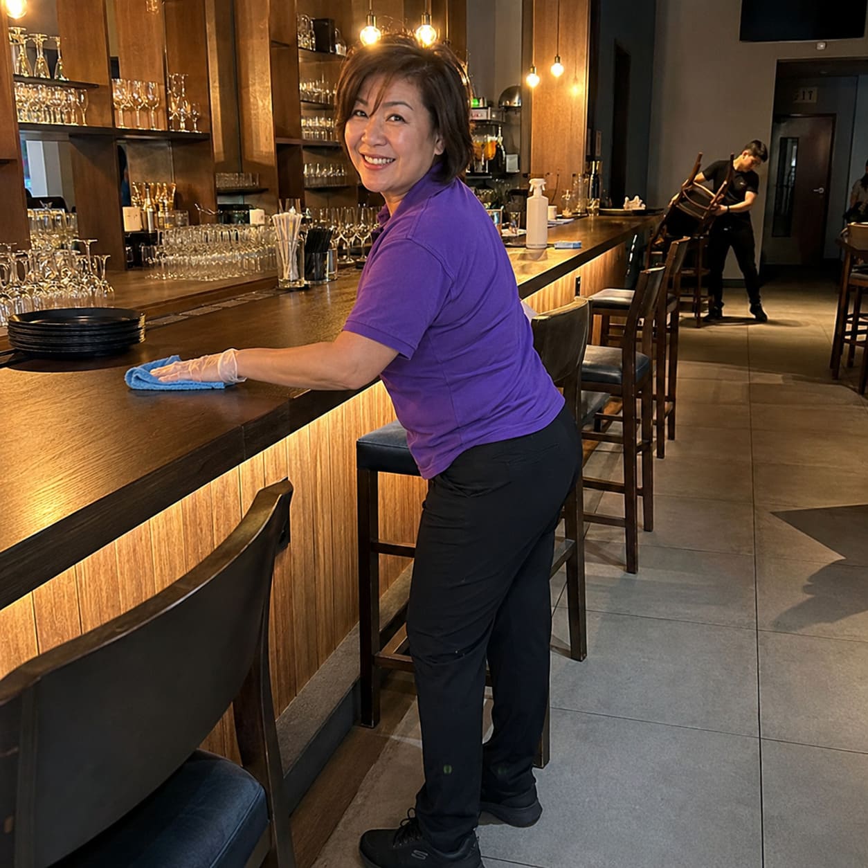 Restaurant cleaner polishing wooden bar and service counter