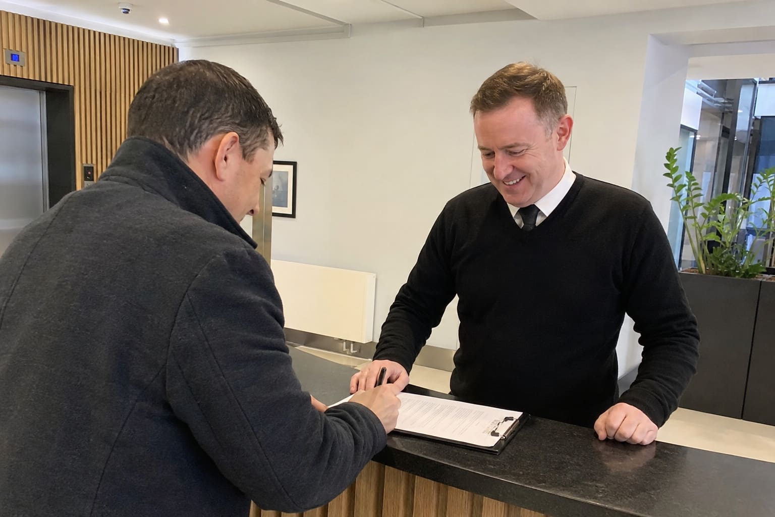 Security officer helping visitor complete reception sign-in paperwork